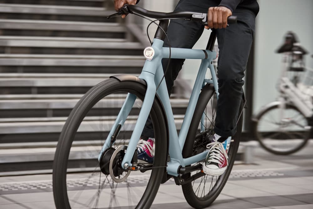 A rider on a blue VanMoof bicycle